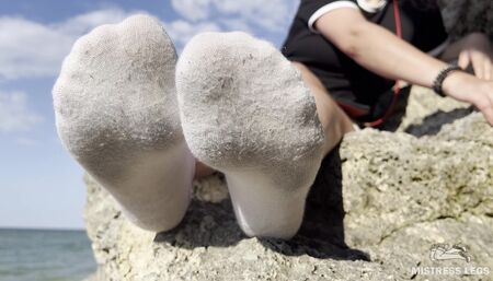 Sexy feet in dirty and terry white socks teasing on the seashore to the sound of the surf
