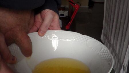 John is pissing in a bowl in closeup