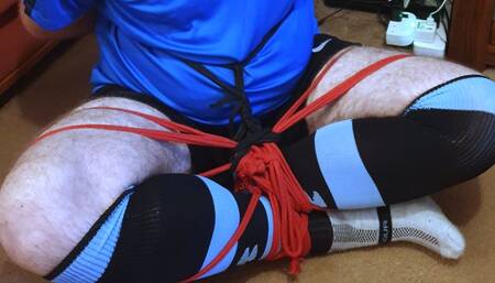 Man in football kit bound and gagged cross-legged by woman 1