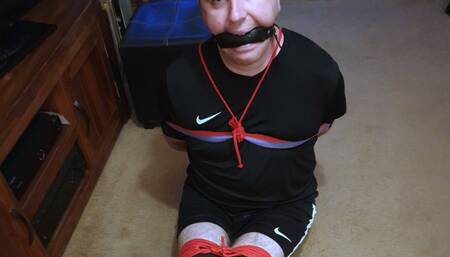 Feet tickling a hogtied footballer in black and red kit