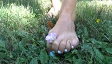 She crushes and rip grass with her small feet plays with flowers with toes