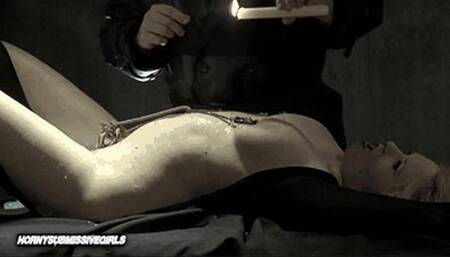 The bondaged slave girl at the table, the hot candle wax on her naked body and her stimulated pussy by vibrator