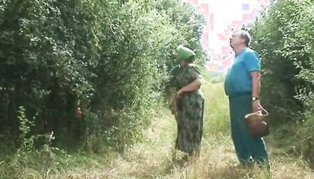 Grandma and a dirty brunette girl are riding cock in the yard