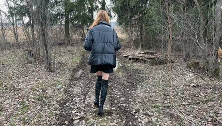 a slender long-legged girl walks in high boots with high heels through puddles and mud, gets stuck in the mud, her boots fill with water