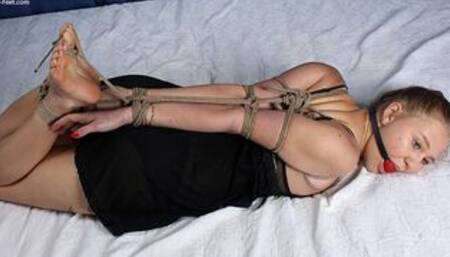 Ballgagged barefoot Nancy, bound to the bed post sitting on the bed with her feet crossed and with her hands above her head, wiggles helplessly (HD WMV)