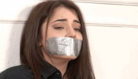 Gagged and bound with duct-tape, barefoot little brunette Kylie Quinn squirms on a hardwood floor!