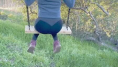 Bubble butt teenage girl shows off her thong on the swing set outdoors