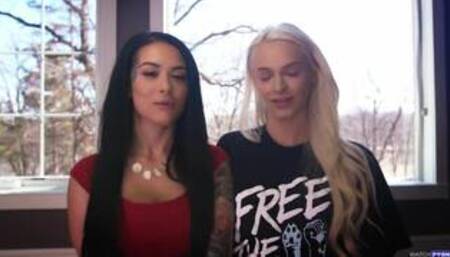 Katrina Jade and Emma Hix on a white coloured bed in a lesbian scene together