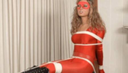 Superhero Melissa Jacobs finds herself tied to a wooden bondage device and unmasked!