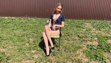 beautiful girl dressed as a police officer sits and plays with her black patent leather high-heeled shoes