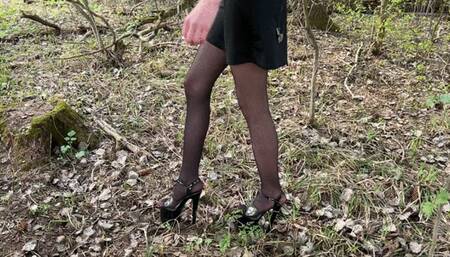 a girl walks through the forest in extremely high heels (30 centimeters), it is very difficult and painful for her to walk, she constantly falls