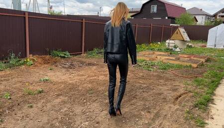the girl is completely in latex and in leather boots with high heels bathes in the mud