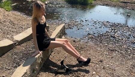 a girl in high-heeled sandals walks through muddy puddles, steps on rubbish and dirt