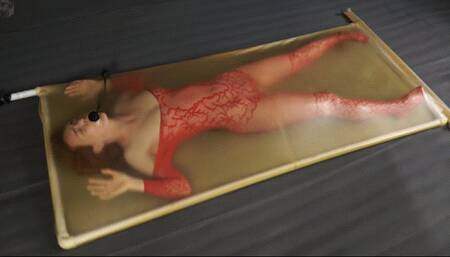 Red costume and pear gag in a latex bed