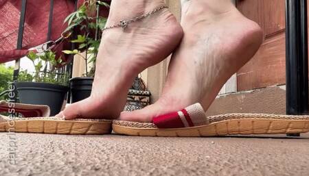 Slippers dangle, arches, and soles show, below my chair pov, long sexy red dress, white toes