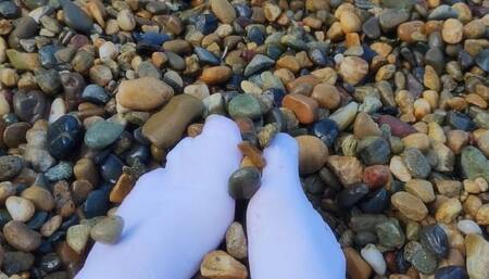 Playing with my feet in white socks with pebbles on the beach