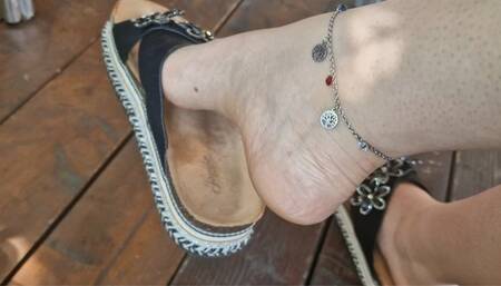 Sexy dangling in a public bar in black sandals