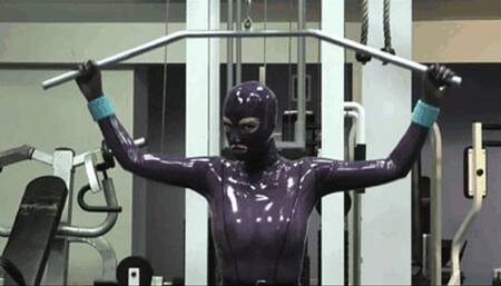 Hot blonde girl in gym makes fitness in purple rubber latex catsuit