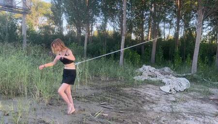 bound girl tries to run barefoot through the slippery mud, but the rope prevents her from escaping