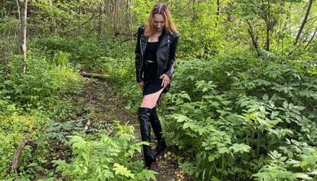 a girl in high-heeled leather boots walks through the mud and falls into a large knee-deep puddle