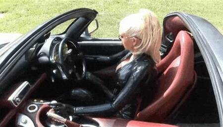 Hot blonde slut in black latex catsuit drives super sport car outdoor
