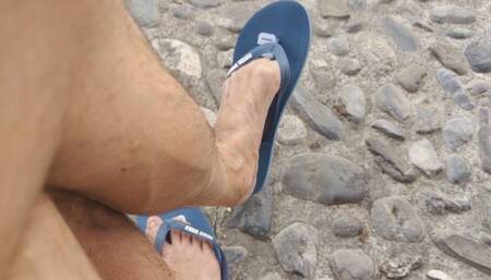 Shoeplay on a public bench with flip flop and dried out feet