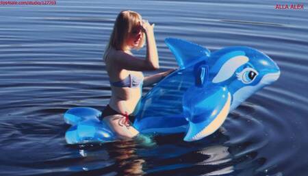 Alla has a hot ride on a transparent blue inflatable whale on the lake on a sunny day!!!