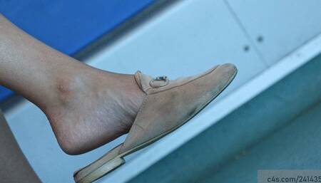 Candid beauty feet in and crossed legs in a slippers dangling