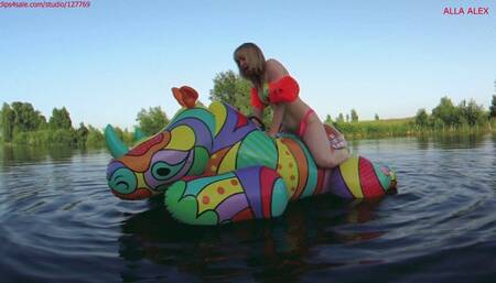 Alla is riding with great pleasure on a big bright squeaky inflatables rhino on the lake!!!