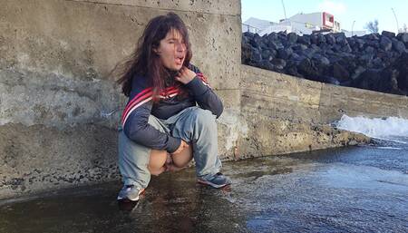 A Cute Expressiagirl in a Tracksuit Sat Down to Pee Near the Ocean