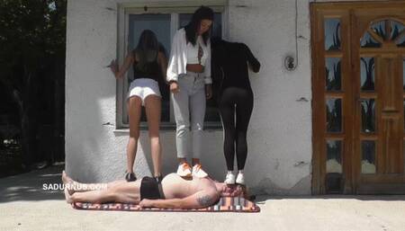 Mistresses trample the slave on the terrace