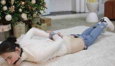 Bound girl with a gag in her mouth writhing on the floor