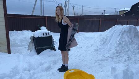 girl walks barefoot in the snow and slides down the hill
