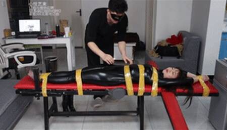 xy32-Chinese girl in full leather clothing is tied and tickled on a bench