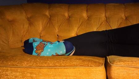 Fifi laying down on the couch in socks then kicking them off