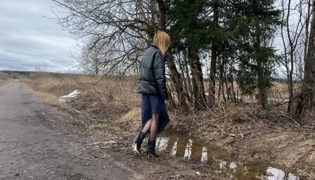 girl in short high-heeled boots walks through deep mud and puddles looking for a way home