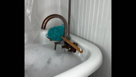 Harmony scrubs her feet in soapy bubbles in the bathtub