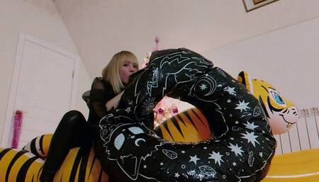 Alla rides on an inflatable tiger and blows up a large, rare inflatable black ring with her mouth