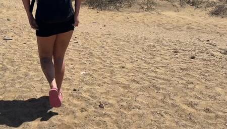 a girl in a short dress pees in the sand with foam on the beach