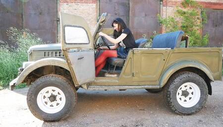 Long-legged beauty in red tights drives and pedal pumpung old Soviet jeep Gaz-69