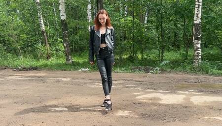 girl in high heels walks along a muddy road and then goes down into a ditch with deep mud to get her shoes even more dirty and destroy her high heels