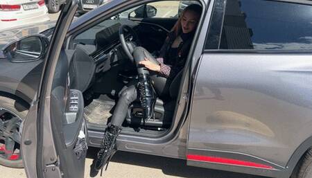 The girl in ballet boots wearing ballet boots, she presses the pedals of the car and plays with his extremely high heels