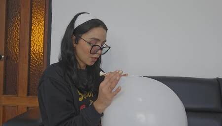 Marianna blows a white balloon full of red kisses to make it pop