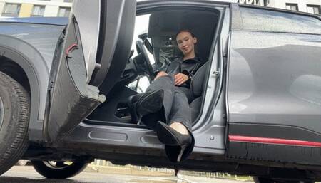 A girl in high-heeled shoes plays with the pedals of a car, first-person and cameraman video