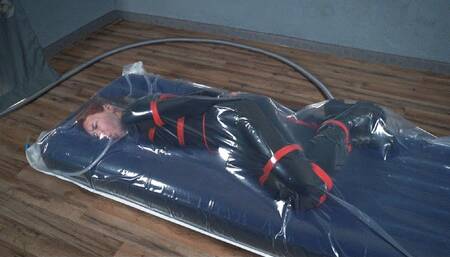 Bondage with red ropes of a special agent in a vacuum bag on an air mattress