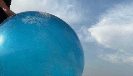 Riding on blue shosu ball on sea beach