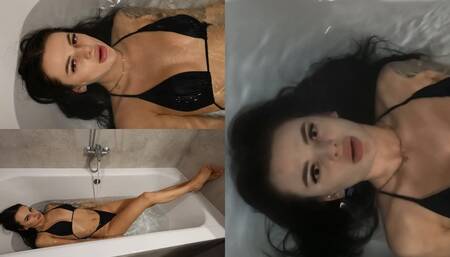 Jade lies in the filling bathtub and goes under the water