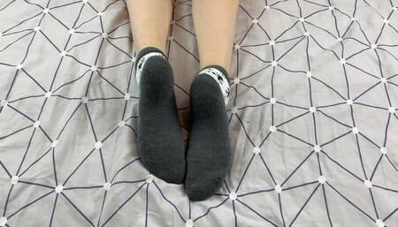 Girl with Long Legs Caresses Her Feet in Gray New Year Socks with Deer