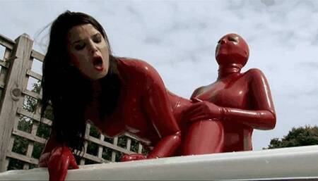 Red latex catsuit lesbians with strap-on in bathtub outdoor