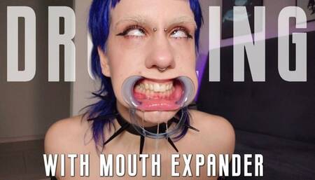 Goth girl's drooling & rolling her eyes with mouth expander
